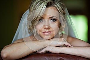 Beautiful innocent blonde bride leaning against chair closeup