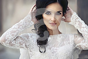 Beautiful innocent brunette bride in white dress posing near church closeup
