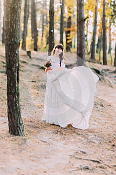 Beautiful innocent young brunette bride in gorgeous long white dress at forest