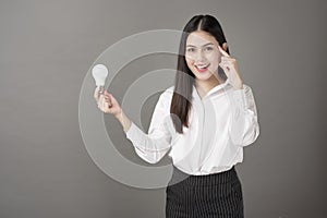 Beautiful intelligent woman is holding light bulb in studio