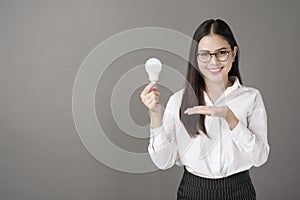 Beautiful intelligent woman is holding light bulb in studio