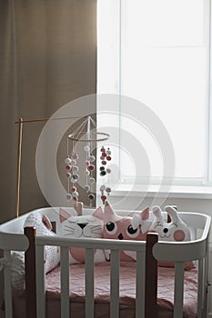 Beautiful interior of baby room with a crib. White crib with pillows and pink blanket in baby room. pastel pink bedding