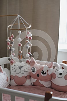 Beautiful interior of baby room with a crib. White crib with pillows and pink blanket in baby room. pastel pink bedding