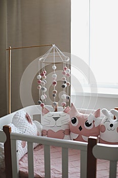 Beautiful interior of baby room with a crib. White crib with pillows and pink blanket in baby room. pastel pink bedding