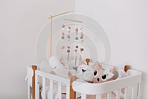 Beautiful interior of baby room. White crib with pillows and pink blanket in baby room.  pink bedding on bed against white wall