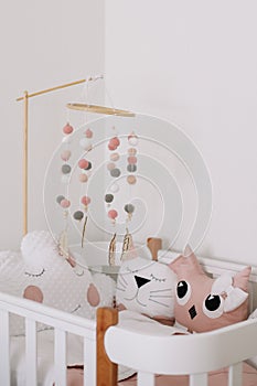 Beautiful interior of baby room. White crib with pillows and pink blanket in baby room.  pink bedding on bed against white wall