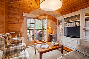 Beautiful interior of cozy living room with view of terrace in a wooden house. Life in a village.