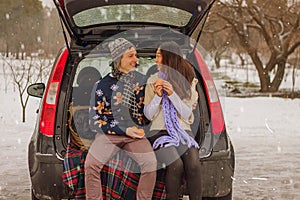 Beautiful international couple relaxing in nature in winter. Romantic meeting of a couple in love in the snow. Young couple sit in