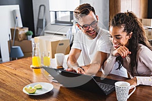 Beautiful interracial couple using laptop computer at home surfing the internet