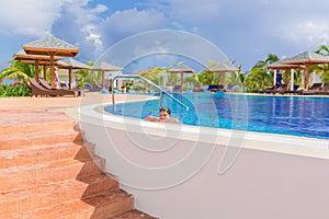 Beautiful inviting view of comfortable cozy swimming pool with smiled little girl relaxing swimming and enjoying her vacation