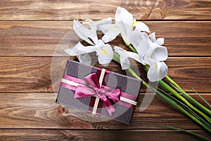 Beautiful irises and gift box on wooden background