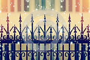 Beautiful iron fence on a blurred background with snow flakes