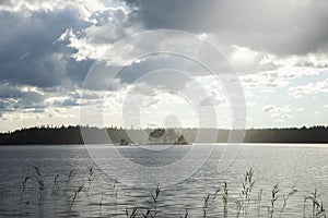 A beautiful island with trees on the huge lake. Rain at sunset makes the sky shine