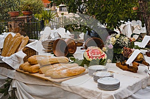 Beautiful Italian garden feast table with freshly baked loaves of bread, fruit and flowers