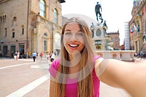 Beautiful Italy. Attractive smiling young woman take self portrait in Piazza del Nettuno square Bologna city, Italy