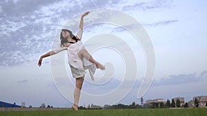 Beautiful Japanese girl in white dress is engaged in ballet on the lawn, slow-motion