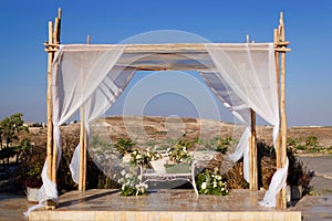 A beautiful Jewish wedding chuppah decorated with bright flowers and white curtains.