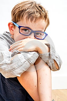 Joyful child hiding giggle in knees and hands for shyness photo