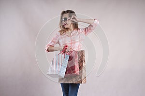 Beautiful joyful girl with person shopping bags in jeans sunglasses studio