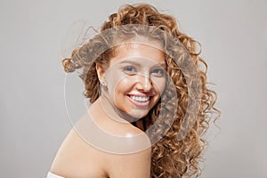Beautiful joyful model woman with wavy hairstyle having fun on gray background. Pretty young woman with curly hair, clear skin,