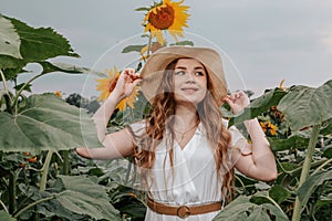 Beautiful joyful woman in blooming sunflower field. Smiling girl with sunflower on field, outdoors. Girl in light beige