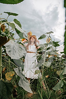 Beautiful joyful woman in blooming sunflower field. Smiling girl with sunflower on field, outdoors. Girl in light beige