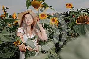 Beautiful joyful woman in blooming sunflower field. Smiling girl with sunflower on field, outdoors. Girl in light beige