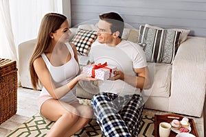 Beautiful joyful woman giving a present to his boyfriend