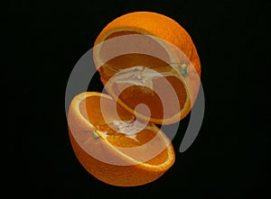 Beautiful juicy orange cut in half soars on a black background