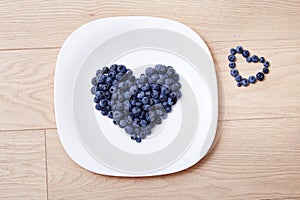 Beautiful juicy ripe natural organic raspberries blackberries blueberries and mint blue tablecloth dots white dish heart shape