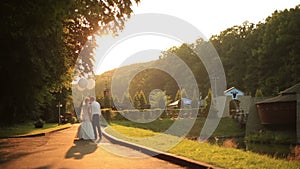 Beautiful just married couple with balloons walking at the golden autumn park and softly kissing on golden sunset