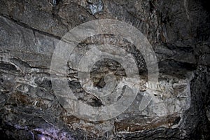 Beautiful karst cave. Rock formations in the cave, stalactites and stalagmites. Abstract gray grunge background. Stone texture