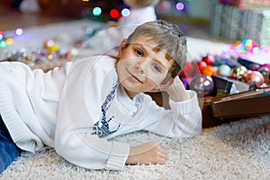 Beautiful kid boy and colorful vintage xmas toys and ball in old suitcase.