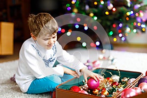 Beautiful kid boy and colorful vintage xmas toys and balls. Child decorating Christmas tree
