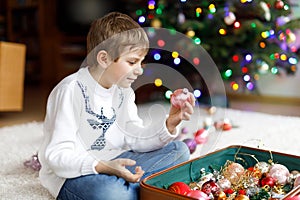 Beautiful kid boy and colorful vintage xmas toys and balls. Child decorating Christmas tree