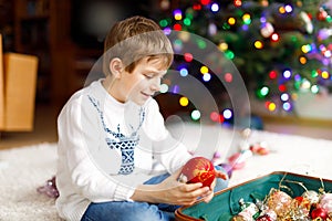 Beautiful kid boy and colorful vintage xmas toys and balls. Child decorating Christmas tree