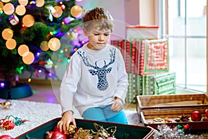 Beautiful kid boy and colorful vintage xmas toys and balls. Child decorating Christmas tree