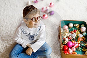 Beautiful kid boy and colorful vintage xmas toys and balls. Child decorating Christmas tree