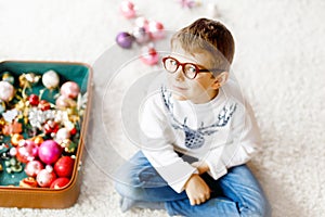 Beautiful kid boy and colorful vintage xmas toys and balls in old suitcase. Little child, school boy in festive clothes