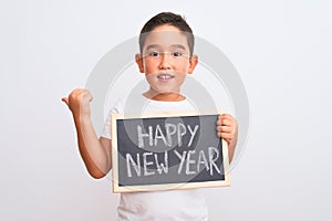 Beautiful kid boy holding blackboard standing over isolated white background pointing and showing with thumb up to the side with