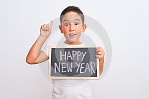 Beautiful kid boy holding blackboard standing over isolated white background surprised with an idea or question pointing finger