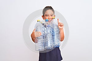 Beautiful kid boy recycling plastic bottles standing over isolated white background surprised with an idea or question pointing