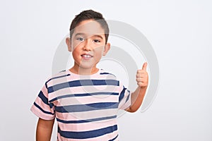 Beautiful kid boy wearing casual striped t-shirt standing over isolated white background doing happy thumbs up gesture with hand