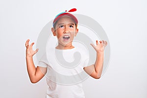 Beautiful kid boy wearing fanny colorful cap with propeller over isolated white background crazy and mad shouting and yelling with