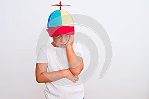 Beautiful kid boy wearing fanny colorful cap with propeller over isolated white background thinking looking tired and bored with
