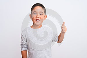 Beautiful kid boy wearing grey casual t-shirt standing over isolated white background doing happy thumbs up gesture with hand