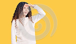 Beautiful kid girl with curly hair wearing casual clothes very happy and smiling looking far away with hand over head