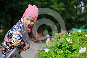 Beautiful kid girl with long hair in rose cap smiling outdoors.
