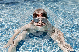 Beautiful kid girl at the pool diving with water goggles. fun outdoors. Summertime and lifestyle concept