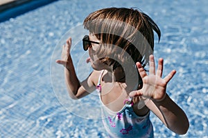 Beautiful kid girl at the pool wearing modern sunglasses. fun outdoors. Summertime and lifestyle concept